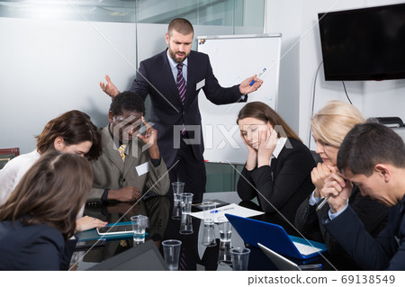 Angry businessman berating managers pointing out shortcomings Angry businessman berating managers pointing out shortcomings 69138549