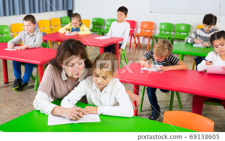 Teacher helping children during lesson Teacher helping children during lesson 69138605