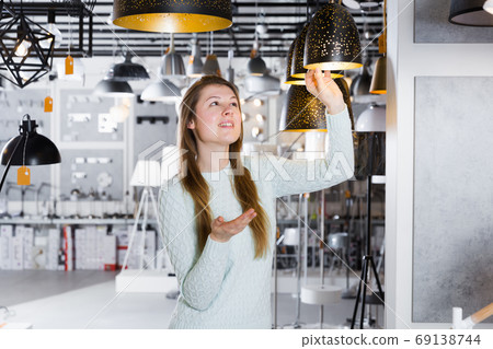 Girl buying plummed lamp in the modern furniture store Girl buying plummed lamp in the modern furniture store 69138744