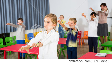 Children stretching with teacher 69138840