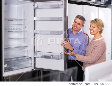 Couple chooses ice-box in shop of household appliances 69138929