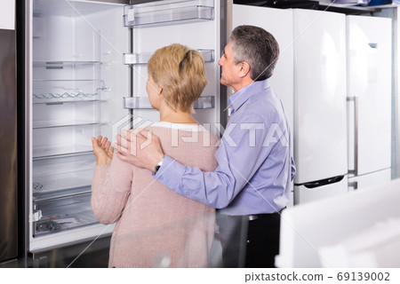 Mature couple chooses refrigerator in store 69139002
