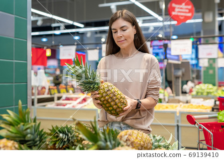 Woman Choosing Pineapple In Store Woman Choosing Pineapple In Store 69139410