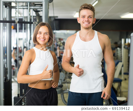 Portrait of couple standing together in gym indoors Portrait of couple standing together in gym indoors 69139412