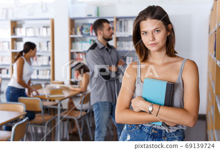 Young woman with book in library 69139724