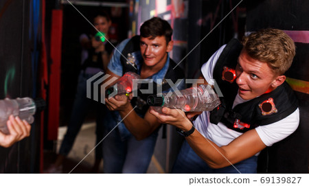 friends standing with laser guns during laser tag game friends standing with laser guns during laser tag game 69139827
