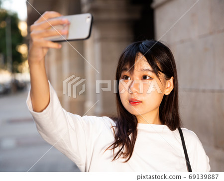 Pretty chinese female tourist making selfie on the background of landmark Pretty chinese female tourist making selfie on the background of landmark 69139887