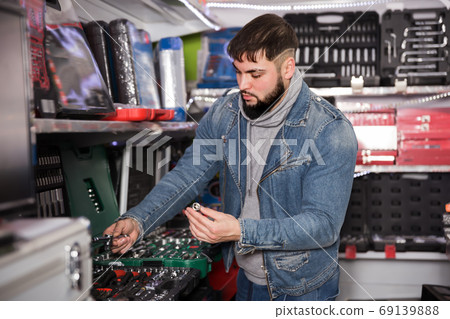 Attentive man is choosing ratchet in store Attentive man is choosing ratchet in store 69139888