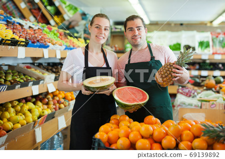 Young man and woman wearing aprons offering fresh fruits 69139892
