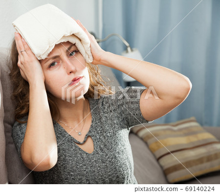 Woman with wet towel on her forehead 69140224