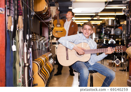 Boy and father choosing acoustic guitar Boy and father choosing acoustic guitar 69140259