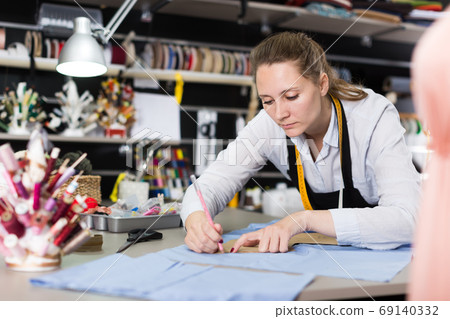 Woman tailor working with marker for modeling clothes at workshop Woman tailor working with marker for modeling clothes at workshop 69140332