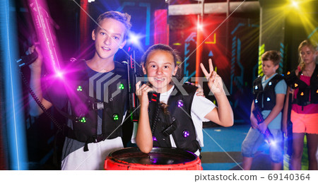 Girl and boy with laser guns on lasertag arena Girl and boy with laser guns on lasertag arena 69140364