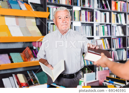 Mature man is purchasing book in bookstore Mature man is purchasing book in bookstore 69140391