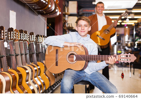 Boy and father choosing acoustic guitar Boy and father choosing acoustic guitar 69140664