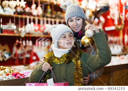 Smiling girl with woman are buying toys for X-mas tree Smiling girl with woman are buying toys for X-mas tree 69141153