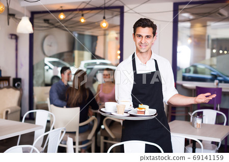 Portrait of happy waiter inviting to coffee 69141159