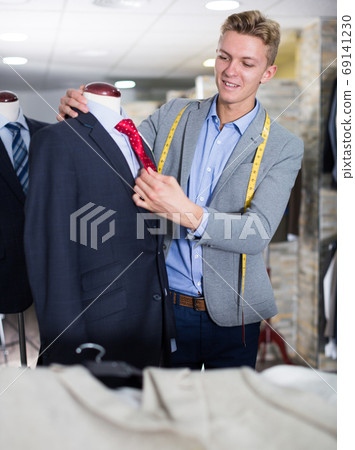Seller in business clothes measuring jacket Seller in business clothes measuring jacket 69141230