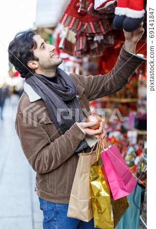 Smiling young man with Christmas toys at fair outside 69141847