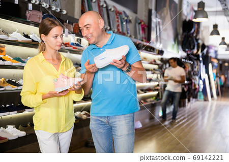Couple of customers choosing male sneakers in showroom Couple of customers choosing male sneakers in showroom 69142221