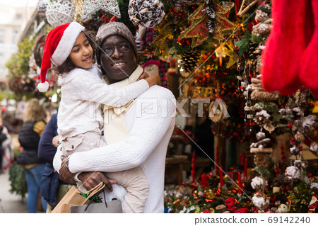 Man holding daughter, looking around at Christmas fair 69142240