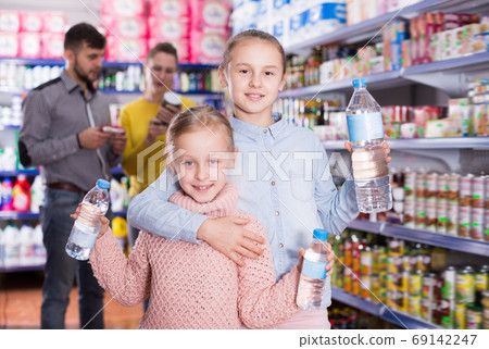 Two small glad sisters holding bottled water 69142247