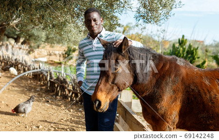 Farmworker carrying horse 69142248
