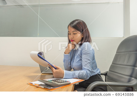 Portrait of Asian businesswoman holding financial reports and thinking 69143886