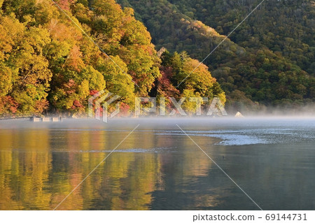 Autumnal forest where the morning sun hits Sentegahama on the misty Lake Chuzenji 69144731
