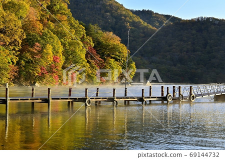 Forest and pier of the autumnal leaves of Sentegahama in the misty Lake Chuzenji 69144732