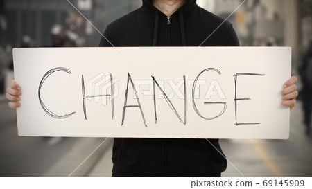 Activist wearing black holds a placard with CHANGE text Activist wearing black holds a placard with CHANGE text 69145909