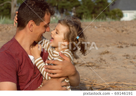 little happy daughter and father laugh and look at each other on beach 69146191