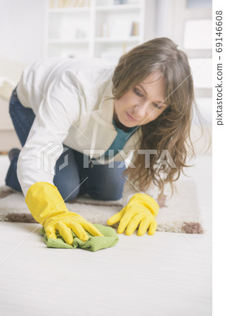 Smiling woman in yellow rubber gloves wiping dust Smiling woman in yellow rubber gloves wiping dust 69146608