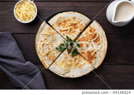 Pieces of quesadilla with mushrooms sour cream and cheese on a plate with parsley leaves. Wooden background copy space. Pieces of quesadilla with mushrooms sour cream and cheese on a plate with parsley leaves. Wooden background copy space. 69146824