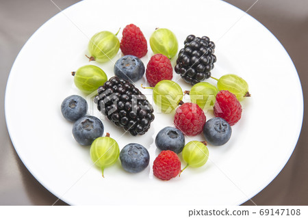 Assorted fresh different berries on a white plate. useful vitami Assorted fresh different berries on a white plate. useful vitami 69147108