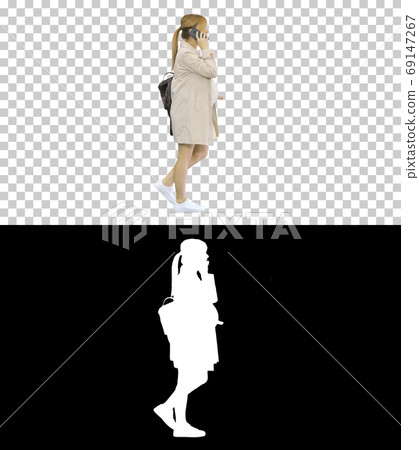 Pregnant woman with backpack walking and talking on the phone, A Pregnant woman with backpack walking and talking on the phone, A 69147267