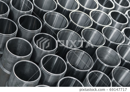 Pattern of metal cylinders stand on table at factory. Steel products to automotive industry. Billet obtained on lathe from steel and cast iron. Circular precision steel parts arranged in rows 69147717