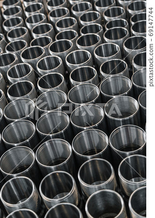 Closeup pattern of shiny circular precision stainless steel industrial machine parts arranged in rows on pallet. Steel products to automotive industry.Billet obtained on lathe from steel and cast iron Closeup pattern of shiny circular precision stainless steel industrial machine parts arranged in rows on pallet. Steel products to automotive industry.Billet obtained on lathe from steel and cast iron 69147744
