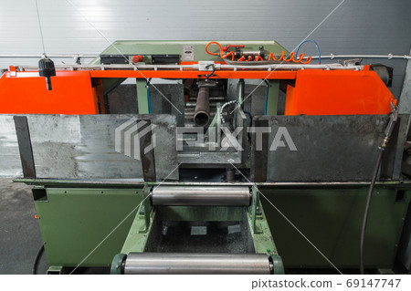 Band saw for industrial high speed cutting metal pipe and using coolant. Raw material for manufacturing process. Precision equipment on manufacture factory line of heavy industry indoors Band saw for industrial high speed cutting metal pipe and using coolant. Raw material for manufacturing process. Precision equipment on manufacture factory line of heavy industry indoors 69147747
