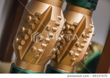 Golden color rock drilling calibrator on shelving in stock. Oil drilling equipment for drilling rig operation on oil platform in oil industry. PDC Polycrystalline Diamond Compact drilling calibrator 69147870
