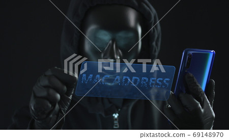 Hacker wearing black mask pulls MAC ADDRESS tab from a smartphone. Hacking concept Hacker wearing black mask pulls MAC ADDRESS tab from a smartphone. Hacking concept 69148970