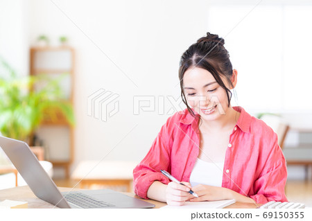 A young woman teleworking in the living room. A young woman teleworking in the living room. 69150355