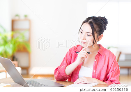 A young woman teleworking in the living room. A young woman teleworking in the living room. 69150356