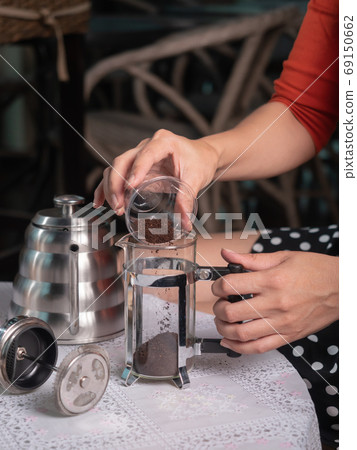 Barista preparing ground coffee into french press cup Barista preparing ground coffee into french press cup 69150662