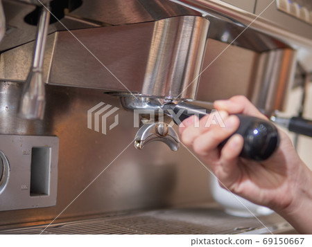 Barista's hand holding portafilter. Barista's hand holding portafilter. 69150667