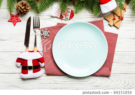 Top view of Christmas dinner on wooden background. Plate, utensil, fir tree and holiday decorations with copy space. New Year time concept 69151850