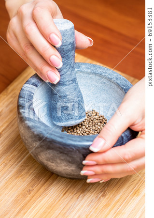 Hands of woman grinding pepper in mortar 69153381
