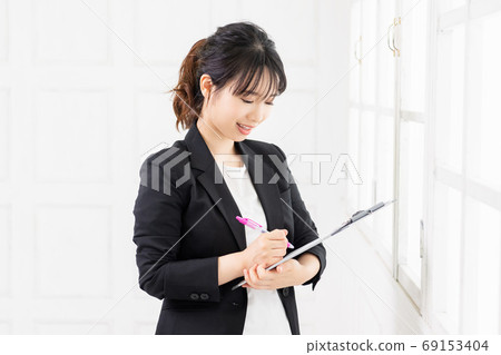 Young business woman listening and recording on clipboard 69153404
