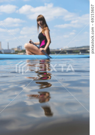 A beautiful woman is engaged in summer active sports on the river on a SUP board A beautiful woman is engaged in summer active sports on the river on a SUP board 69153607