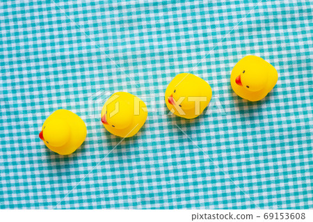 Row of yellow rubber ducks on green check pattern fabric background. Business leadership concept 69153608